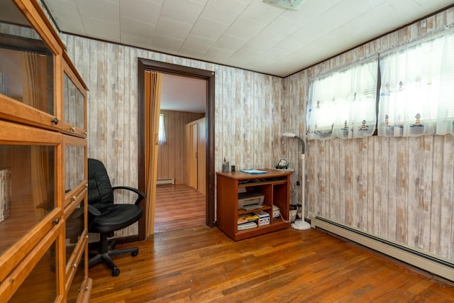 office with hardwood / wood-style flooring, wooden walls, and a baseboard radiator