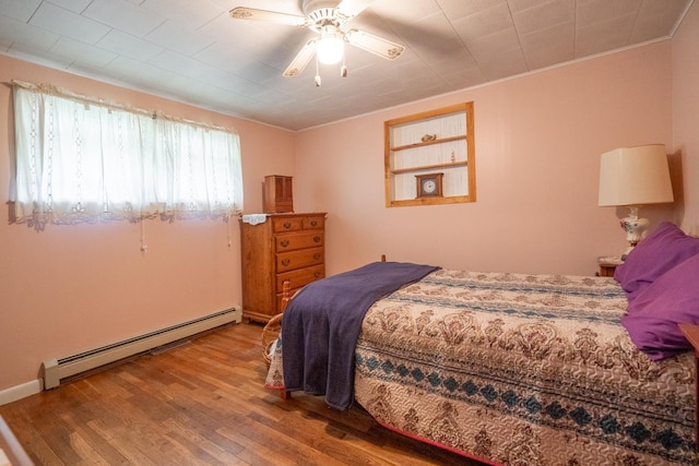 bedroom featuring baseboard heating, ceiling fan, hardwood / wood-style floors, and crown molding