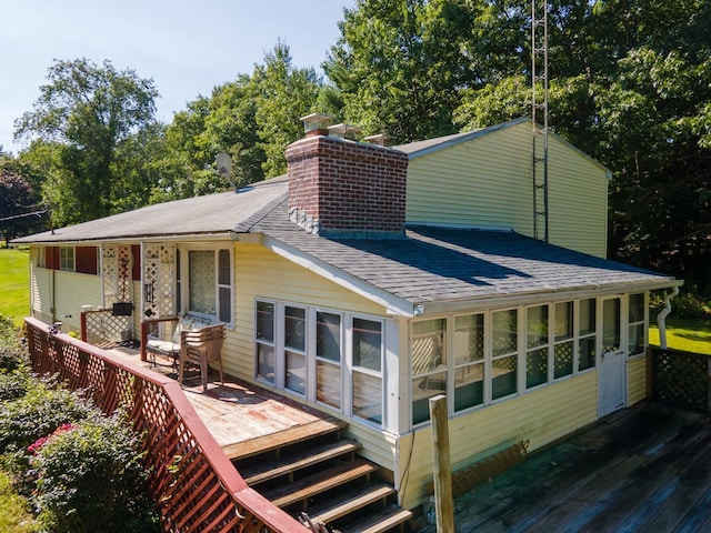 back of property with a deck and a sunroom