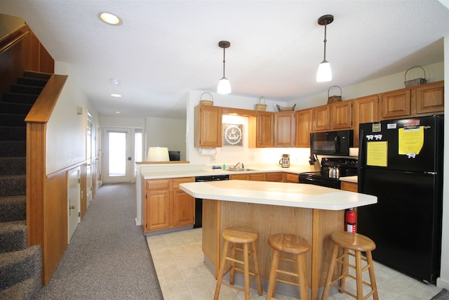 kitchen with a breakfast bar, black appliances, sink, hanging light fixtures, and kitchen peninsula