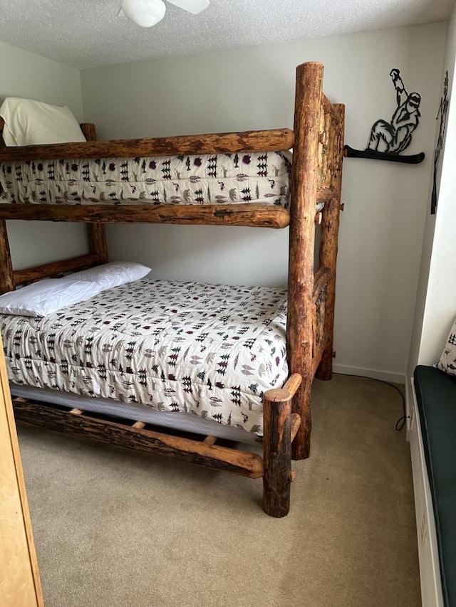 bedroom with ceiling fan, carpet floors, and a textured ceiling