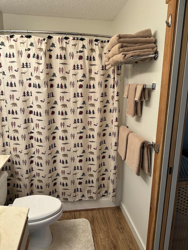 full bathroom featuring shower / bath combo, wood-type flooring, a textured ceiling, toilet, and vanity