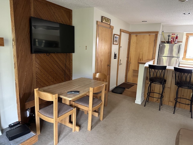 carpeted dining area with a textured ceiling