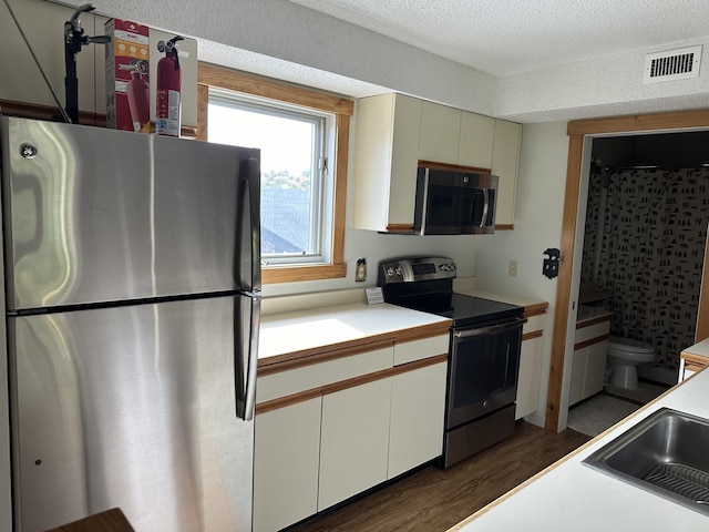 kitchen featuring dark wood-type flooring, white cabinets, sink, a textured ceiling, and stainless steel appliances