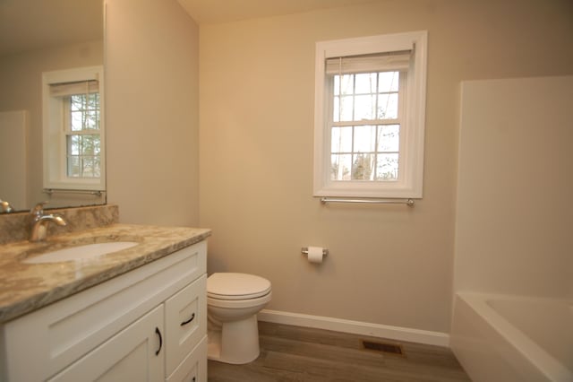 bathroom with vanity, wood-type flooring, a bathing tub, and toilet