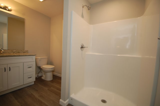 bathroom featuring hardwood / wood-style flooring, vanity, toilet, and a shower