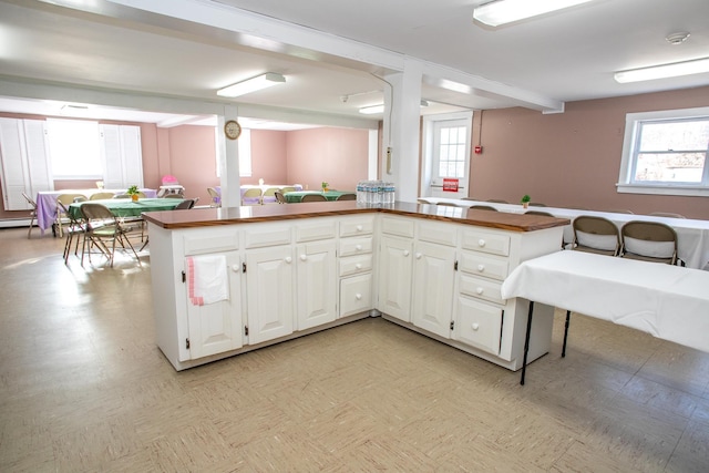 kitchen with beam ceiling, white cabinetry, and kitchen peninsula