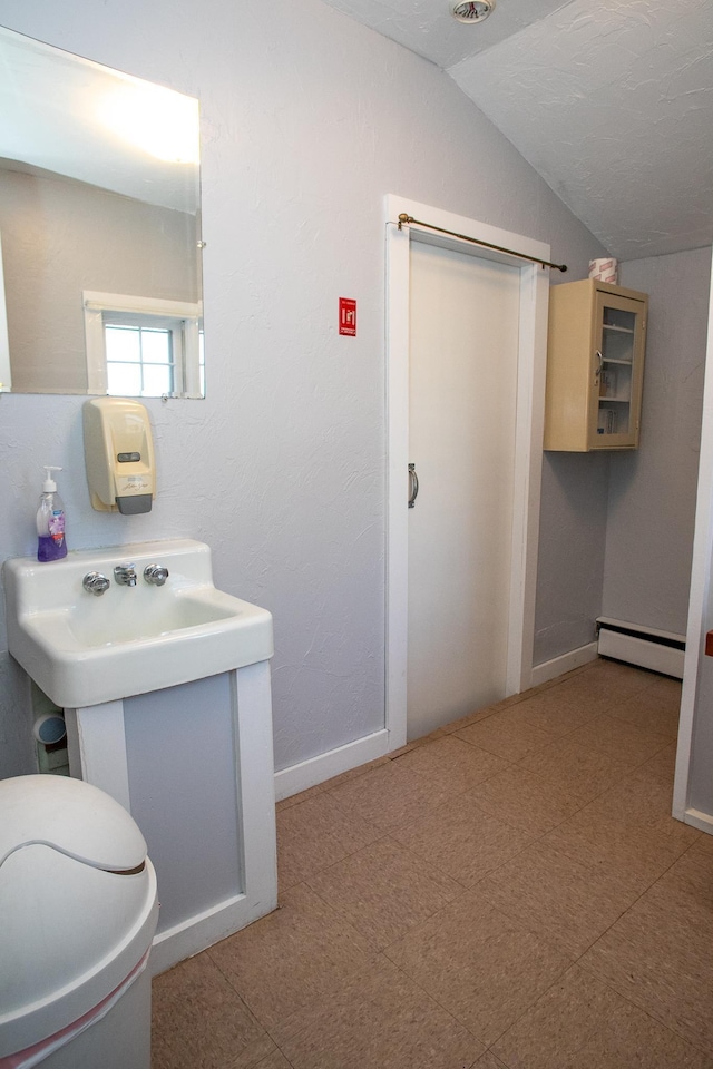 bathroom with toilet, lofted ceiling, and a baseboard radiator