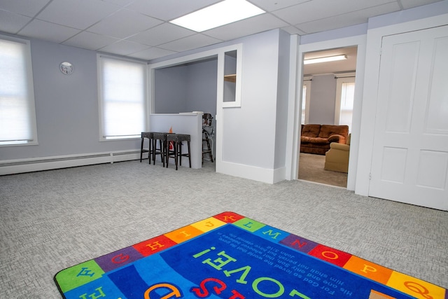 recreation room featuring carpet, a healthy amount of sunlight, and a baseboard heating unit