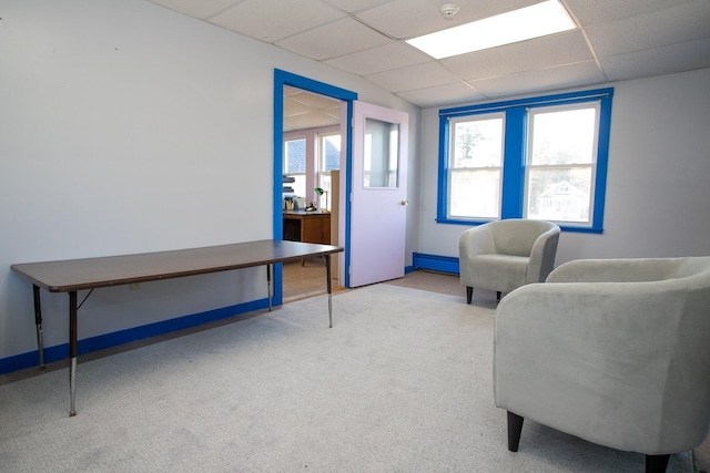 sitting room with light carpet, a drop ceiling, and a baseboard radiator