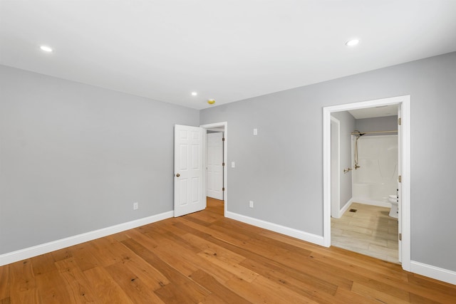 unfurnished bedroom with light wood-type flooring and connected bathroom