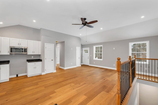 living room featuring ceiling fan, a wealth of natural light, light hardwood / wood-style flooring, and vaulted ceiling