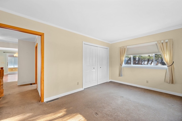 unfurnished bedroom featuring crown molding, light carpet, and a closet