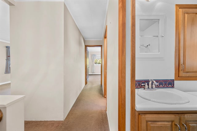 hallway featuring light carpet and sink