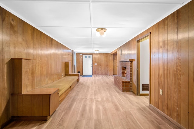 hallway featuring light hardwood / wood-style flooring, wooden walls, and crown molding