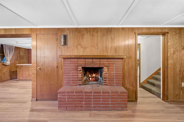 living room featuring light hardwood / wood-style floors, a brick fireplace, and wood walls