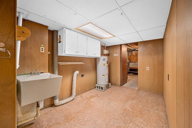 bathroom featuring sink, a paneled ceiling, wood walls, and water heater