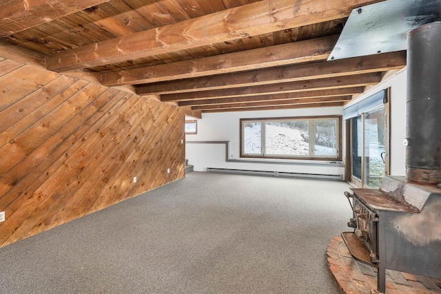 unfurnished living room featuring beam ceiling, a wood stove, a baseboard heating unit, wooden walls, and carpet