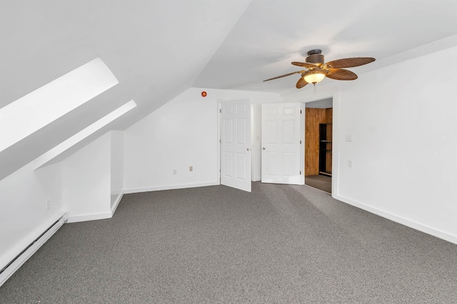 additional living space with baseboard heating, ceiling fan, vaulted ceiling with skylight, and carpet floors