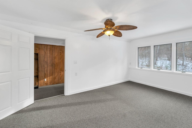 unfurnished room with carpet, ceiling fan, and wood walls