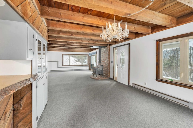 interior space featuring beam ceiling, a wood stove, baseboard heating, and an inviting chandelier