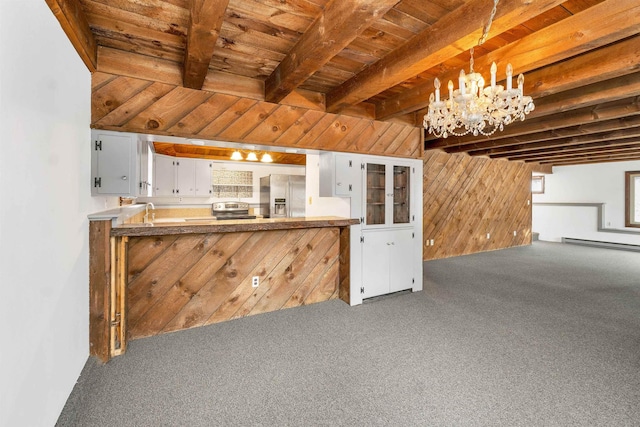 kitchen featuring hanging light fixtures, wooden walls, appliances with stainless steel finishes, white cabinetry, and kitchen peninsula