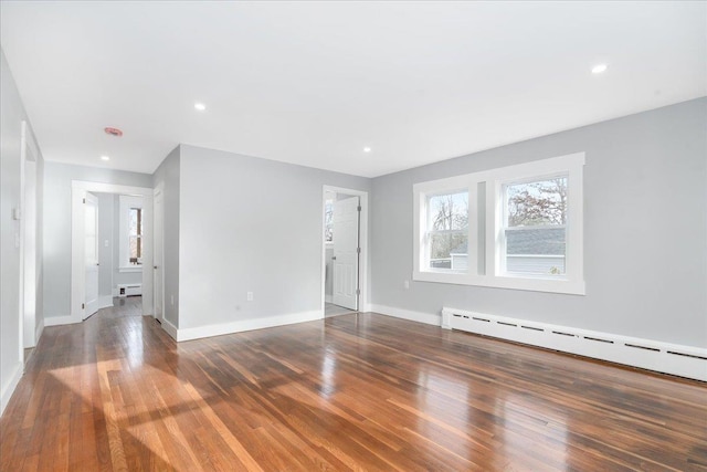 unfurnished room with baseboard heating and dark wood-type flooring