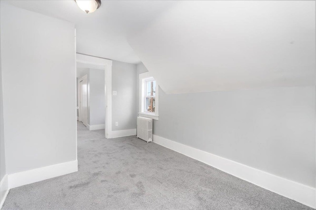 additional living space with light colored carpet, radiator, and vaulted ceiling