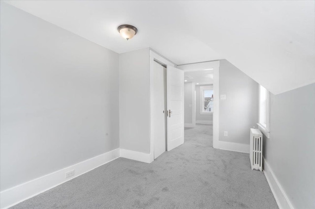 additional living space with light carpet, radiator heating unit, and lofted ceiling