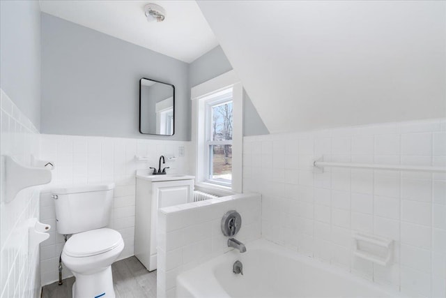 bathroom featuring vanity, a tub to relax in, toilet, and tile walls