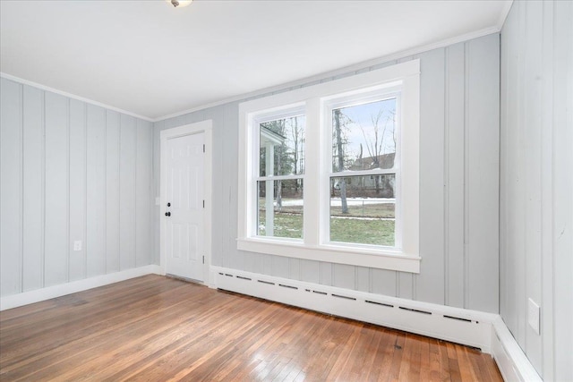 spare room featuring hardwood / wood-style floors, plenty of natural light, crown molding, and a baseboard radiator