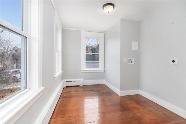 spare room with dark hardwood / wood-style flooring, a wealth of natural light, and a baseboard radiator