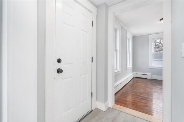 foyer entrance with light wood-type flooring and a baseboard heating unit