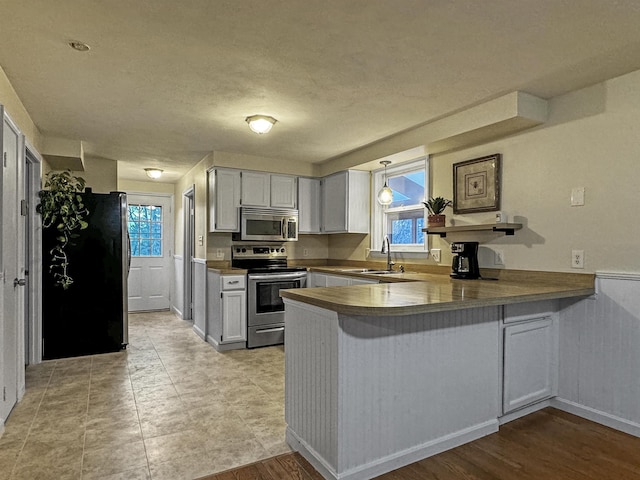 kitchen with white cabinets, kitchen peninsula, sink, and appliances with stainless steel finishes