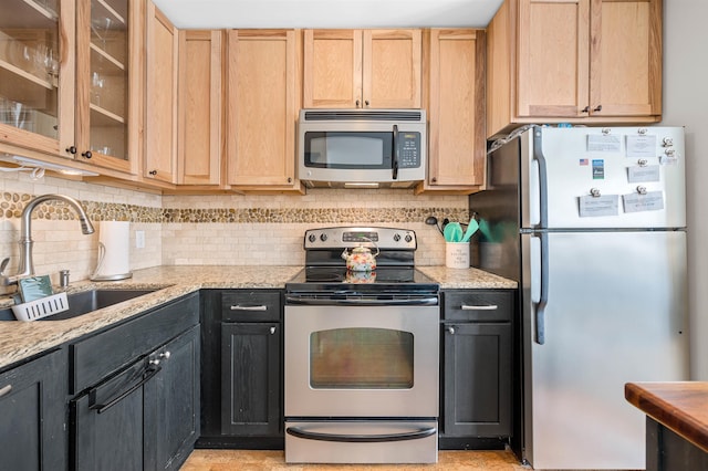 kitchen featuring light stone countertops, appliances with stainless steel finishes, decorative backsplash, light brown cabinetry, and sink