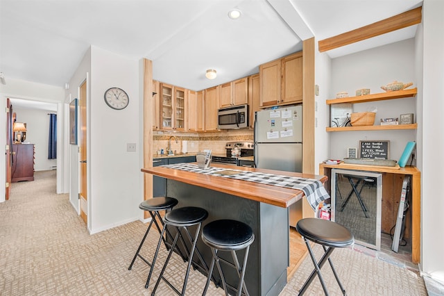 kitchen featuring decorative backsplash, appliances with stainless steel finishes, a breakfast bar, sink, and butcher block counters