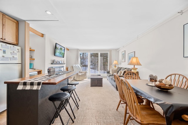 interior space featuring light brown cabinetry, floor to ceiling windows, light colored carpet, white refrigerator, and a kitchen island