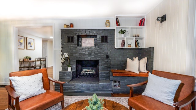 living area featuring a brick fireplace and wood finished floors