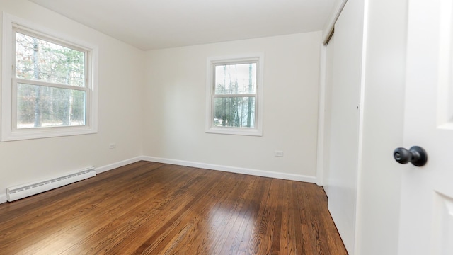 unfurnished room with baseboards, dark wood-style flooring, a baseboard radiator, and a healthy amount of sunlight