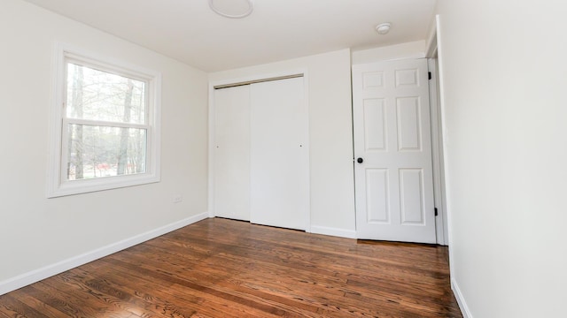 unfurnished bedroom with dark hardwood / wood-style floors and a closet