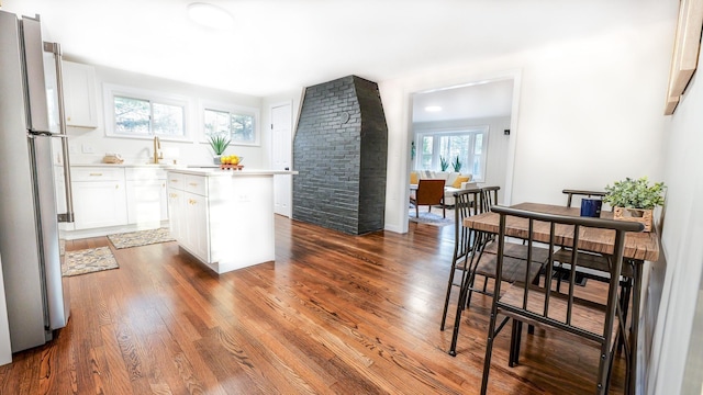 kitchen with white cabinets, light countertops, freestanding refrigerator, a center island, and dark wood finished floors