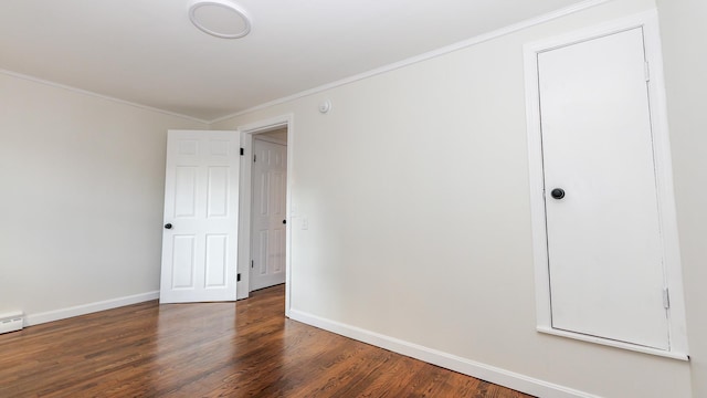 empty room featuring dark wood-type flooring and ornamental molding