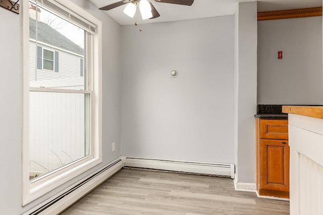 spare room with ceiling fan, light wood-type flooring, and baseboard heating