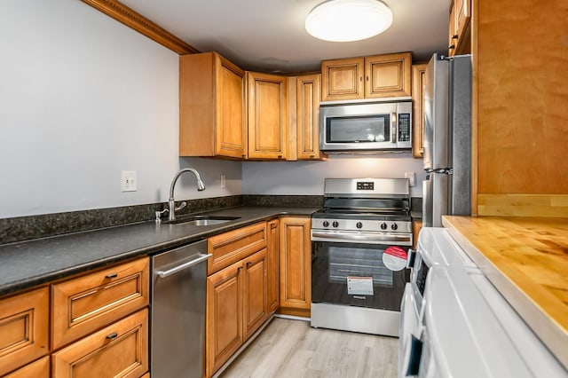 kitchen with sink, wooden counters, crown molding, appliances with stainless steel finishes, and light wood-type flooring