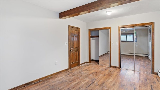 unfurnished bedroom featuring beamed ceiling, light wood-type flooring, and a baseboard heating unit