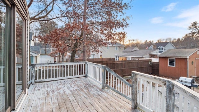 wooden deck with a storage unit, a fenced backyard, grilling area, a residential view, and an outdoor structure