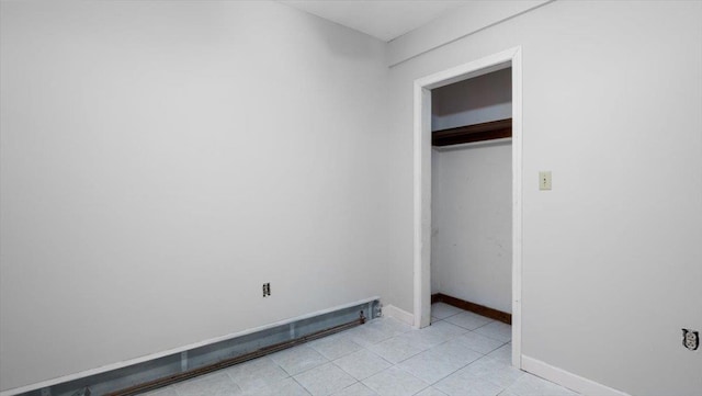 unfurnished bedroom featuring a closet and a baseboard heating unit