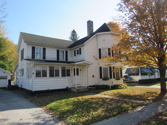 front facade with a garage and an outbuilding