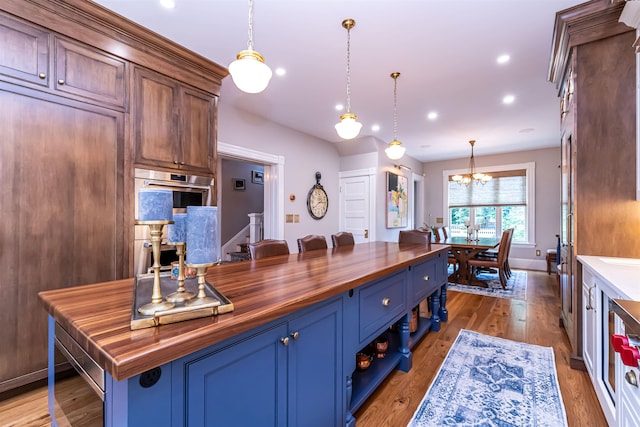 kitchen featuring blue cabinetry, an inviting chandelier, butcher block countertops, pendant lighting, and a kitchen island