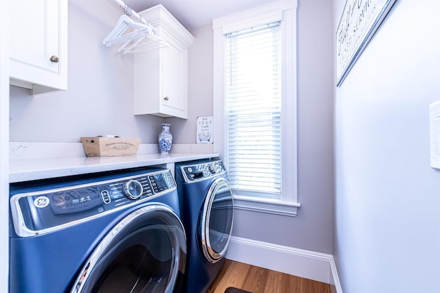 laundry area featuring cabinets, wood-type flooring, and washing machine and dryer